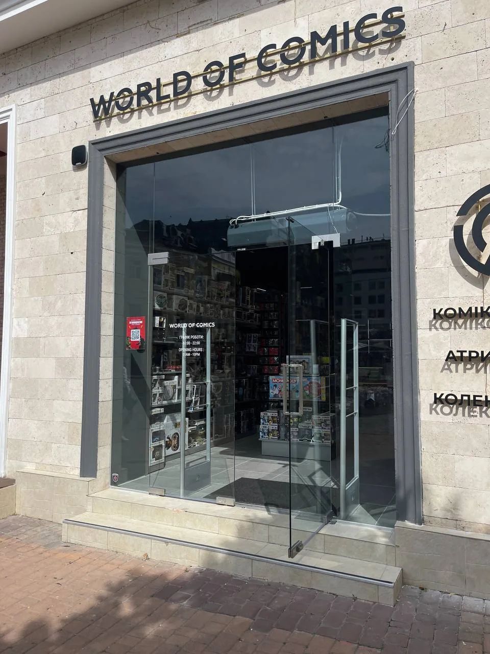 Glass entrance of the World of Comics shop in a stone facade