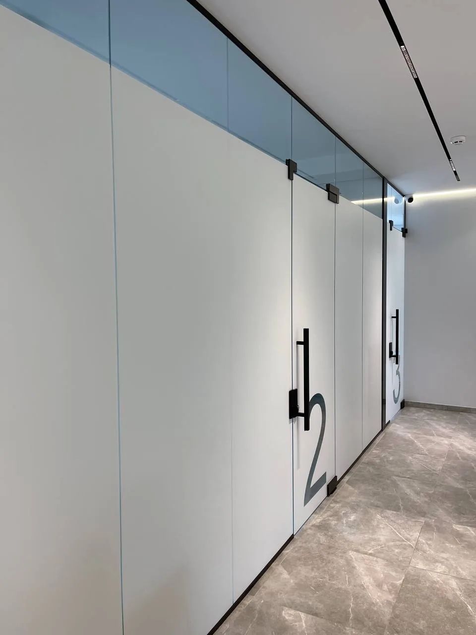Corridor of a clinic with frosted glass partitions and numbered doors